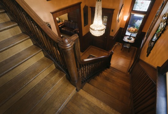 Restored interior of a historic St. Louis home featuring an original dark wood staircase, intricate millwork, and a classic foyer layout